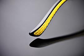 Gros plan photo d’une branche de lunettes noire et jaune texturée avec un reflet net sur fond sombre