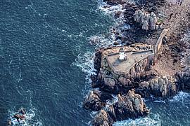 Photographie Le Phare du Paon se dresse fièrement face à la Manche. Cette prise de vue aérienne souligne le contraste entre la pierre brute et la force de l'océan.