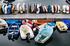 Annexes de bateaux multicolores amarrées à un ponton gris et rangées sur un rack dans le port de Lezardrieux.