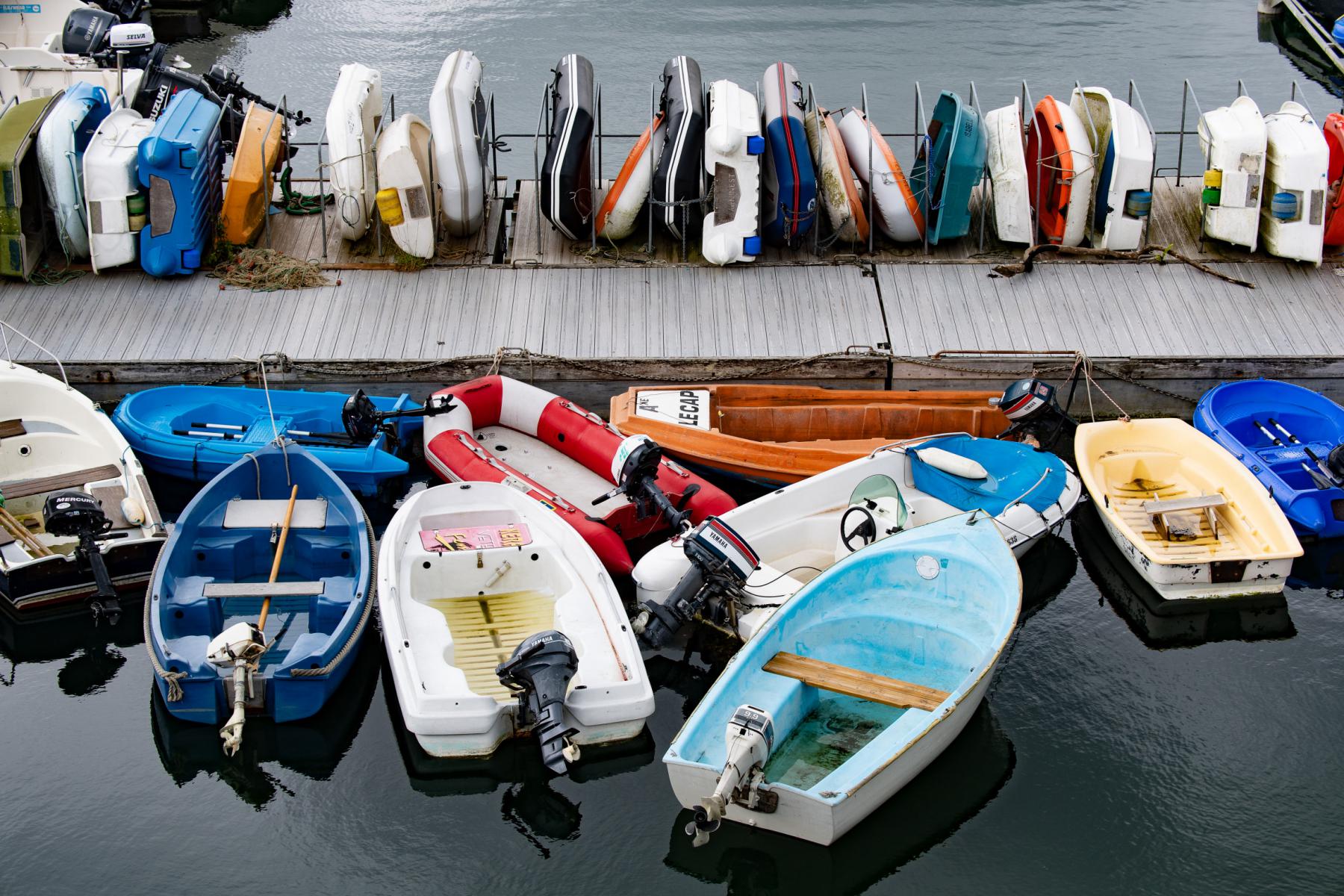 Annexes de bateaux multicolores amarrées à un ponton gris et rangées sur un rack dans le port de Lezardrieux.
