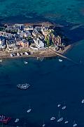 Maisons de pierre au bord de l’eau turquoise avec des bateaux au mouillage dans le port breton de Loguivy sous une lumière zénithale.