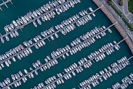 Alignement géométrique de bateaux de plaisance blancs amarrés aux pontons du port de Trébeurden vus du ciel.