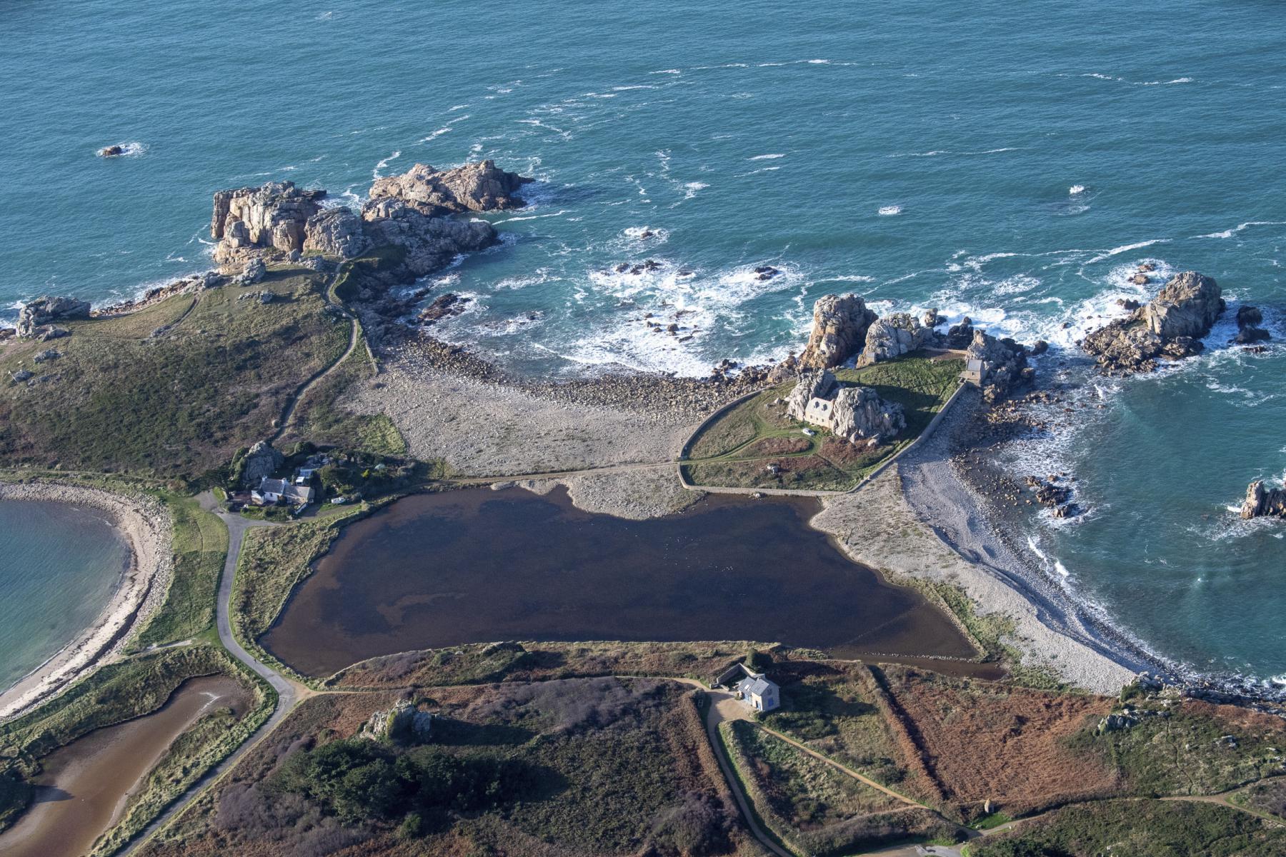 Vue du ciel de Kastel Meur encadrée par deux rochers géants au bord de l’eau turquoise et du Gouffre de Plougrescrant.