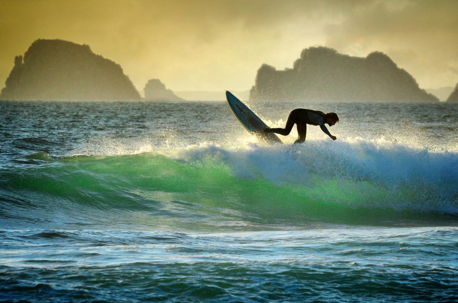 Photographie Session de surf entre emeraude et doré à La Palud à la tombée du jour, avec les Tas de Pois en arrière plan.