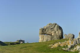 Gros rocher en forme de tête animale sur une lande d’herbe verte sous un ciel bleu à Ouessant en Bretagne.