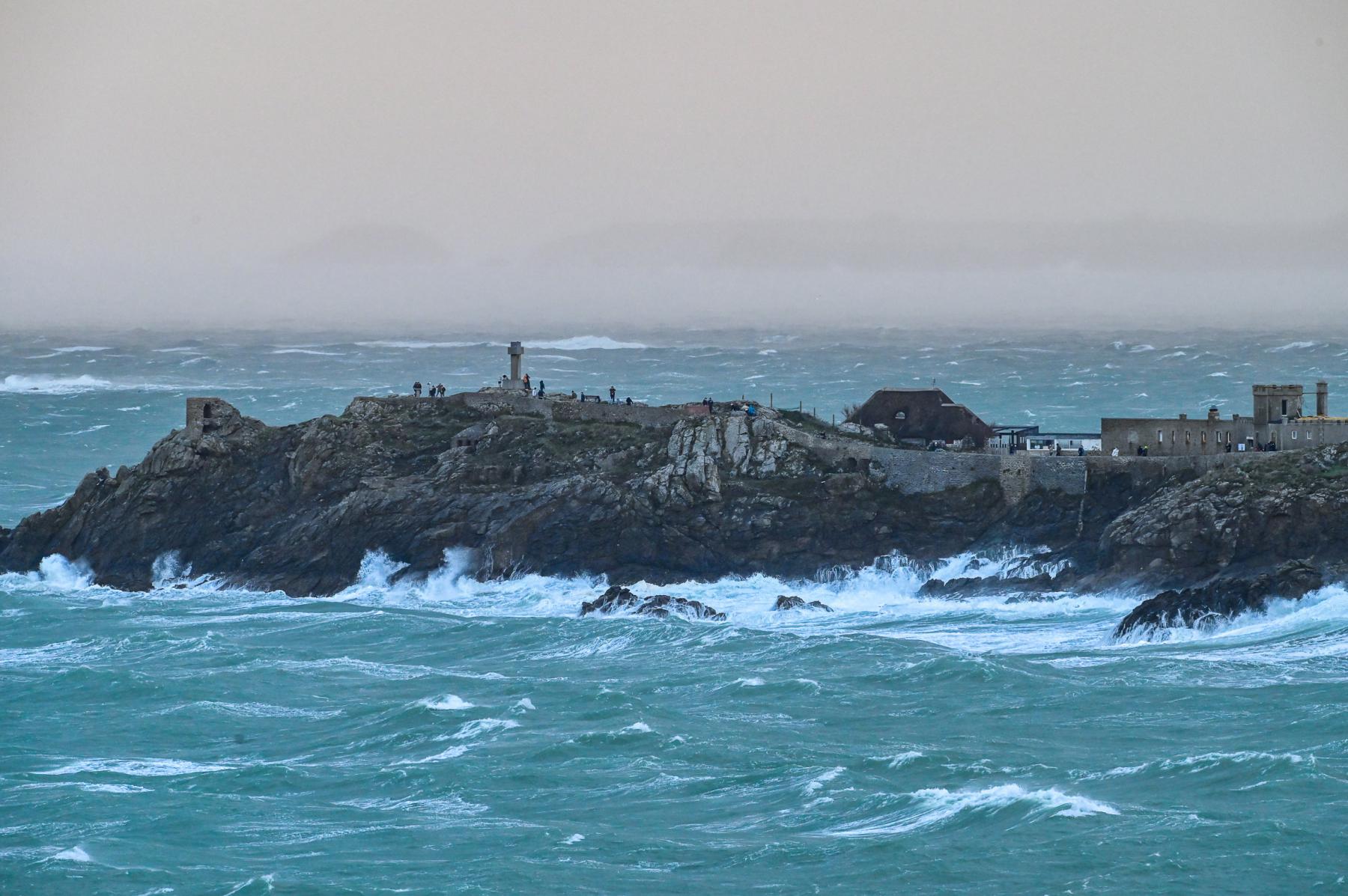 Vagues tumultueuses s’écrasant contre les rochers de la pointe du Décollé à Saint-Lunaire sous un ciel de tempête gris.
