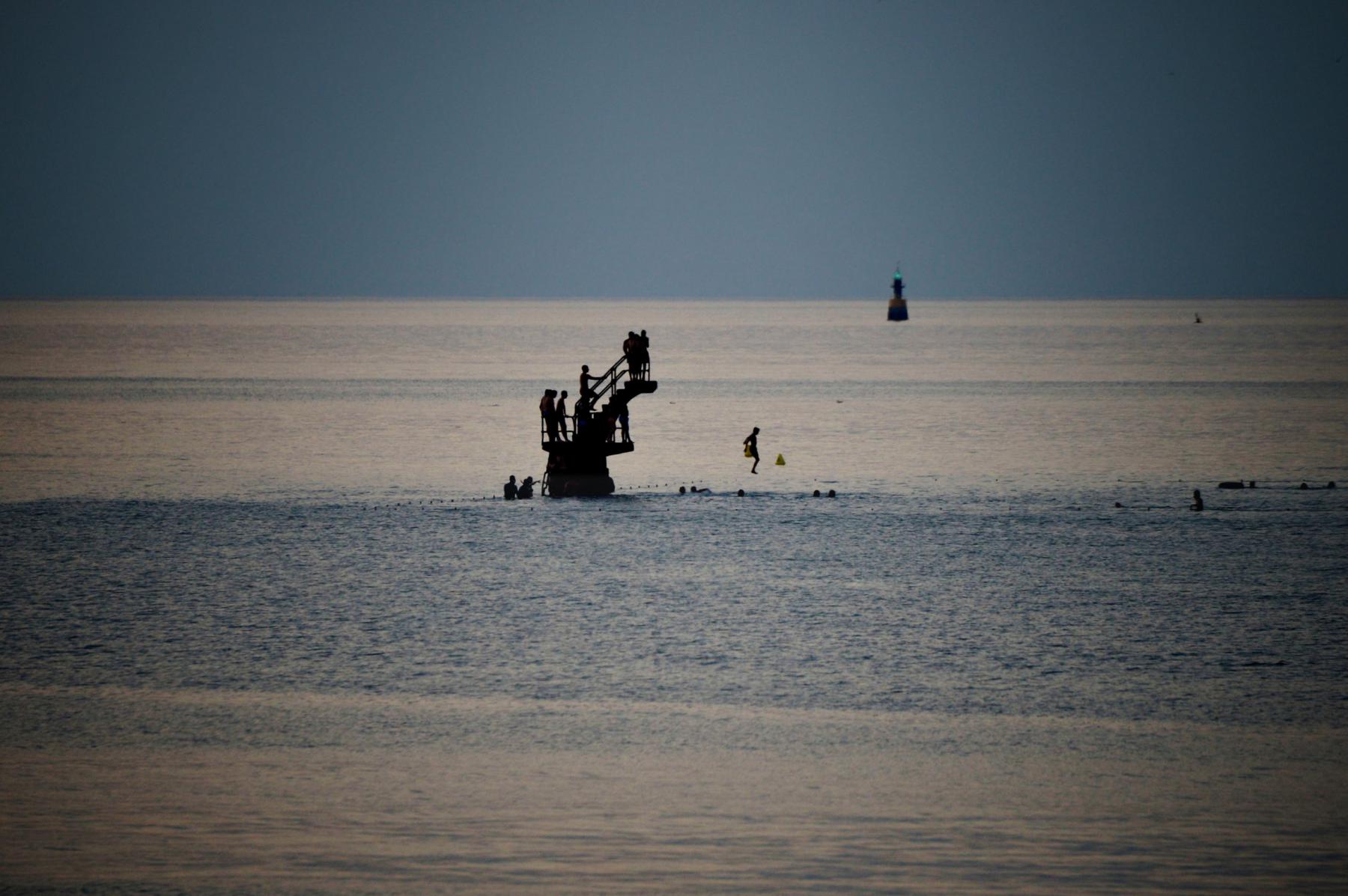 Photographie L'iconique plongeoir de de Bon-Secours s'anime sous la lumière douce du soir. Une scène de vie estivale capturée devant St Malo, un soir d'été