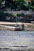 Deux marcheurs sur une jetée en pierre à marée basse près d’une balise verte à Port-Navalo en Bretagne.
