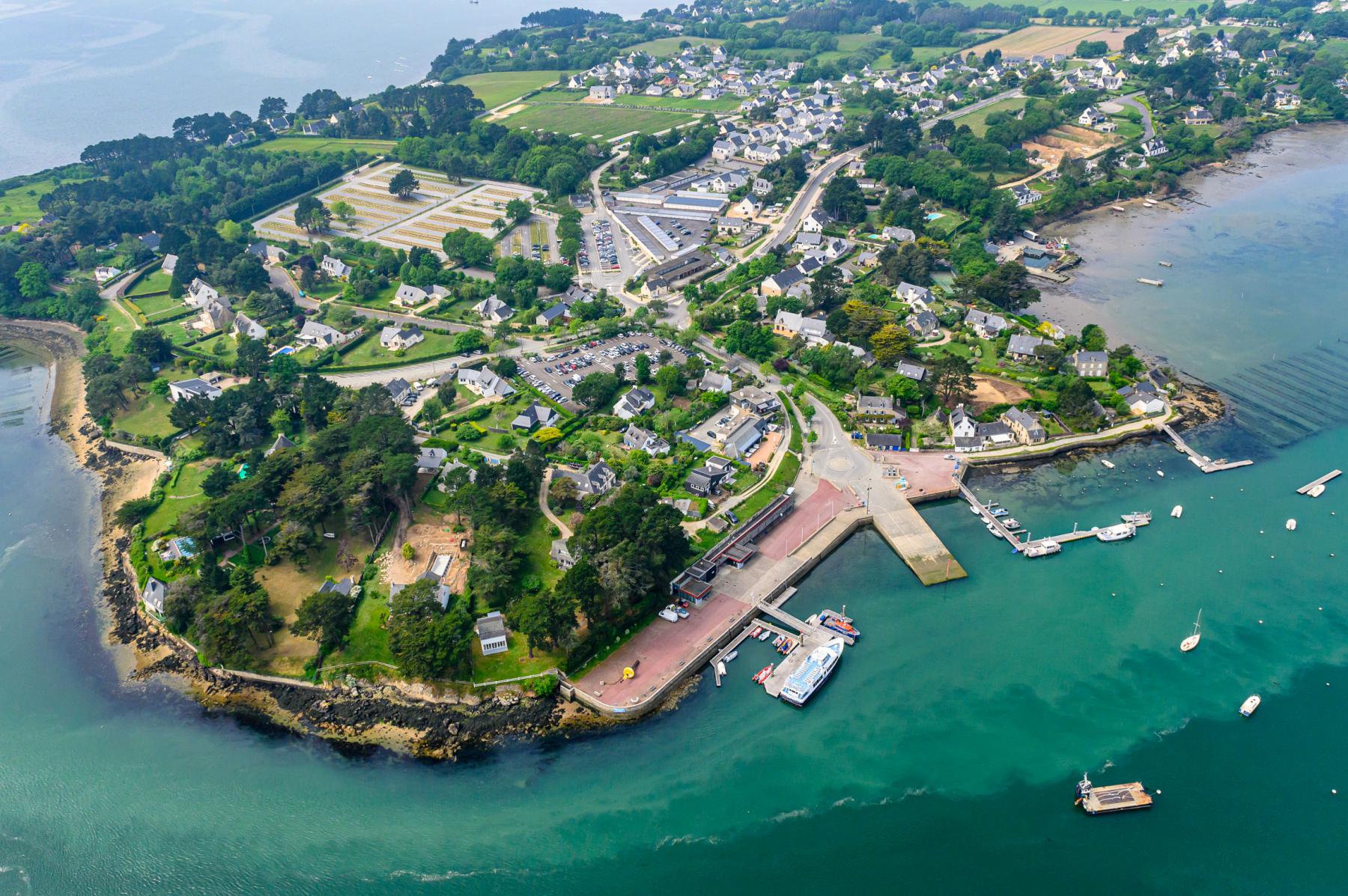 Vue aérienne de l’embarcadère de Port Blanc à Baden, quai en pierre, bateaux sur l’eau turquoise et maisons bretonnes.