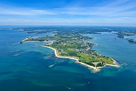 Vue aérienne de la pointe de Kerpenhir à Locmariaquer, eaux turquoise et plages de sable sous un ciel bleu en Bretagne.