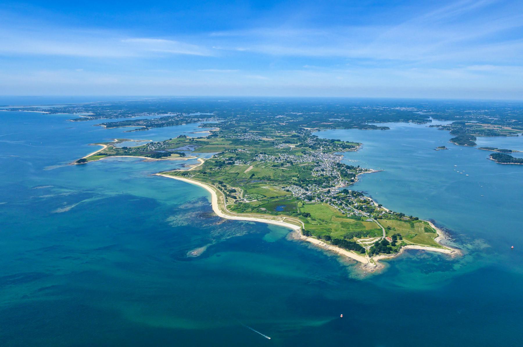 Vue aérienne de la pointe de Kerpenhir à Locmariaquer, eaux turquoise et plages de sable sous un ciel bleu en Bretagne.