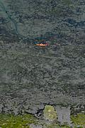 Vue de dessus d’un kayak orange solitaire glissant sur les eaux texturées et les fonds marins de la Marle à Séné.
