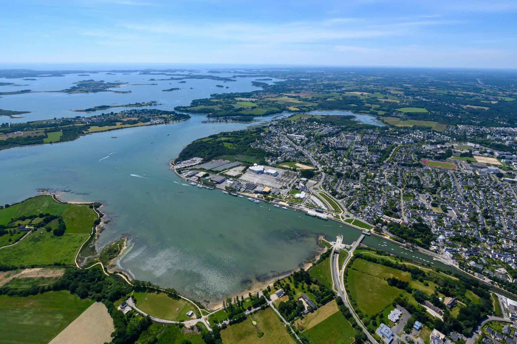 Vue aérienne du littoral de Vannes avec la Pointe des Émigrés, les eaux bleues du Golfe et les zones urbaines verdoyantes.