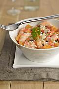 Salade de crevettes et agrumes dans un bol blanc strié avec fourchette en argent et herbes fraîches sur tissu gris.