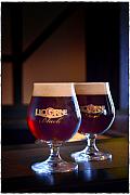 Deux verres ballon de bière brune Licorne Black avec une mousse onctueuse sous un éclairage clair-obscur en studio.