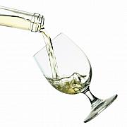 Vin blanc versé d’une bouteille dans un verre à pied incliné, éclaboussures et mouvement du liquide sur fond blanc.