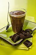 Crème dessert au chocolat onctueuse dans son verre, posée sur une assiette verte avec des carrés de chocolat noir 