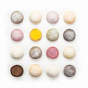 Alignement symétrique de mochis colorés et saupoudrés de sucre sur fond blanc vus de dessus avec coupes transversales.
