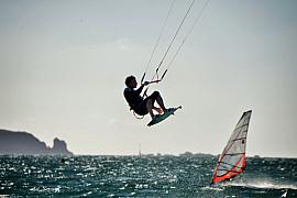 Kitesurfeur en saut acrobatique au-dessus de l’eau à Saint-Malo, voile de windsurf et côtes en arrière-plan.