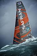 Voilier IMOCA Safran sur mer agitée avec vagues blanches et ciel sombre lors de la Route du Rhum à Saint-Malo.