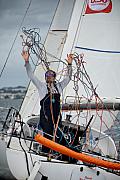 Skipper sur un voilier Mini 6.50 manipulant des cordages colorés sur le pont par temps couvert devant Concarneau