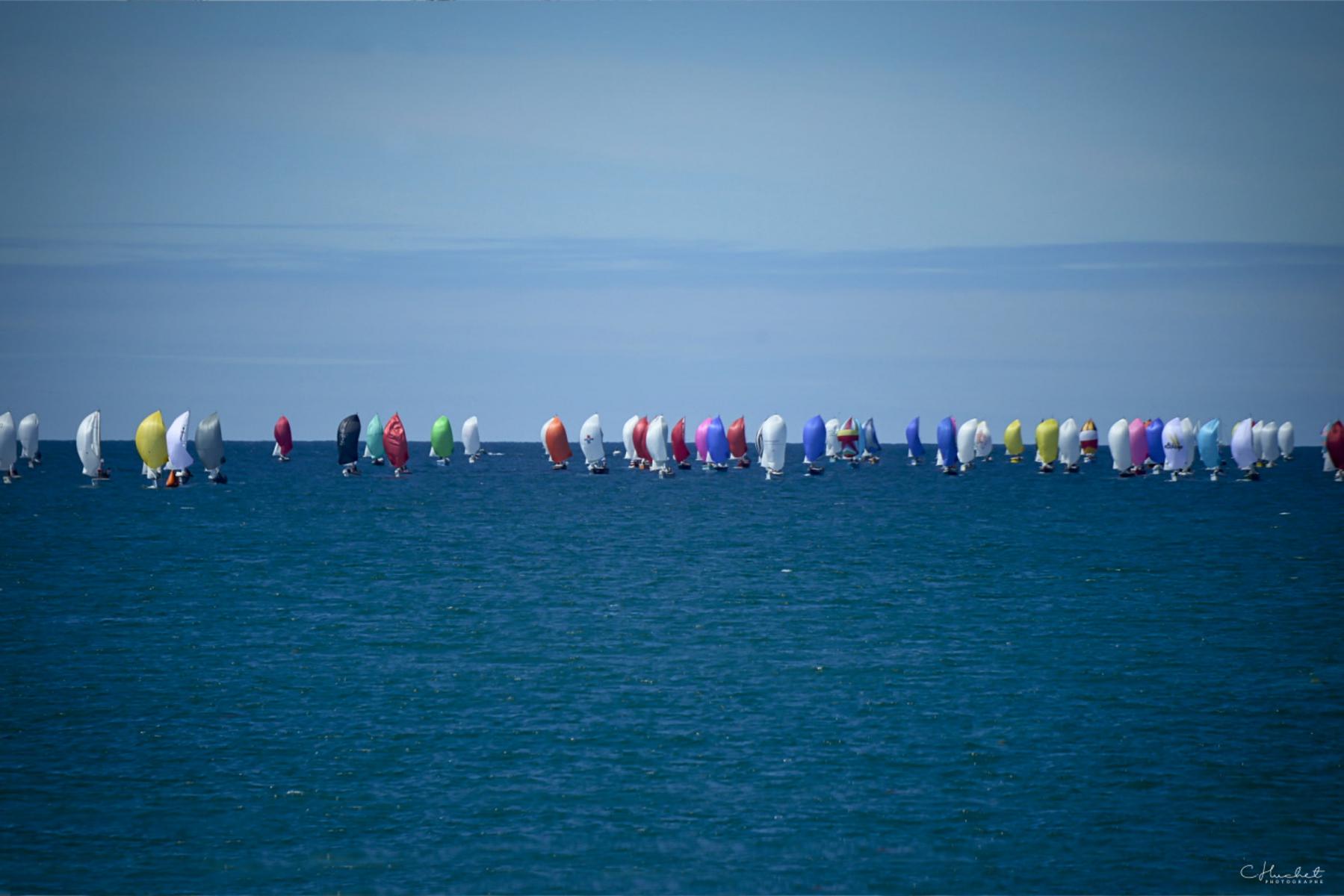 Nombreux voiliers aux spinnakers multicolores alignes sur l horizon marin a Saint-Malo sous un ciel bleu