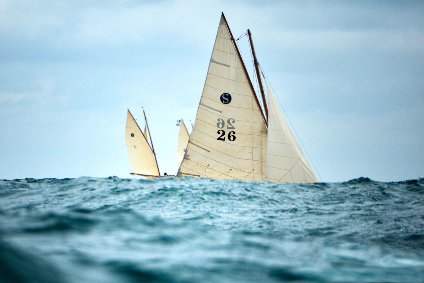 Voilier traditionnel à voiles beiges naviguant sur une mer agitée en Bretagne sous un ciel nuageux.