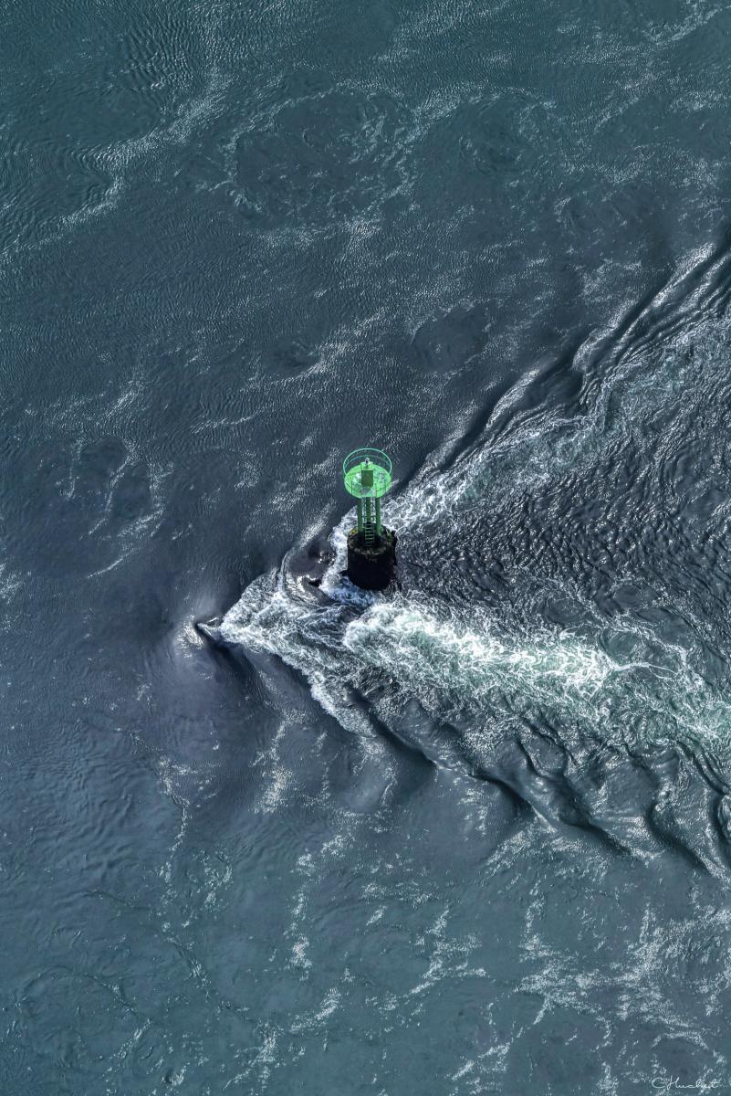 Balise maritime verte entourée par les remous et les courants de l’eau sombre dans le Golfe du Morbihan.