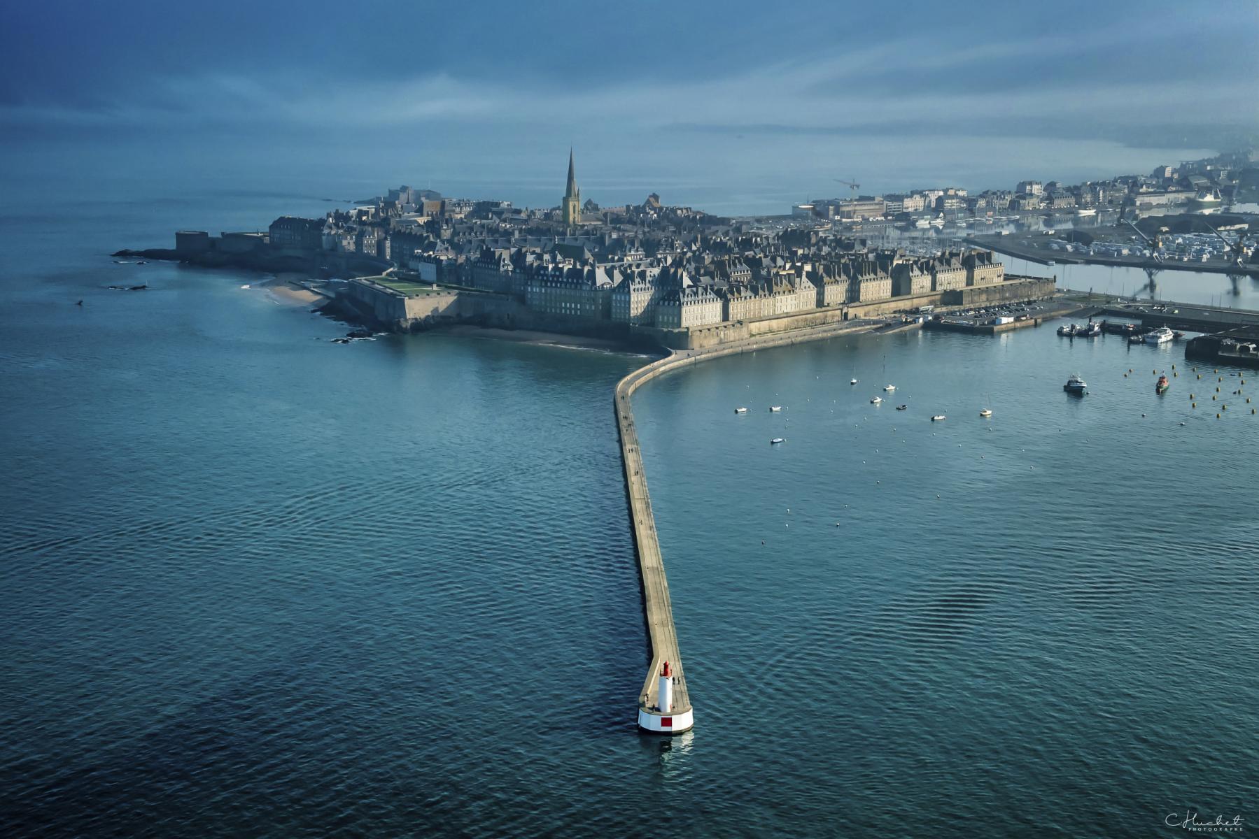 Vue aérienne du môle des Noires avec son phare blanc et rouge face aux remparts de Saint-Malo en Ille-et-Vilaine.