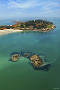 Vue plongeante sur les eaux turquoise entourant les îlots rocheux et la plage de l’archipel des Ebihens en Bretagne.
