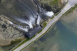 Vue zénithale d’un moulin à marée en pierre avec l’eau s’écoulant par les vannes d’une digue dans le Morbihan en Bretagne.