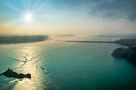 Vue aérienne du barrage de la Rance sous la brume avec reflets solaires sur mer turquoise à Dinard.