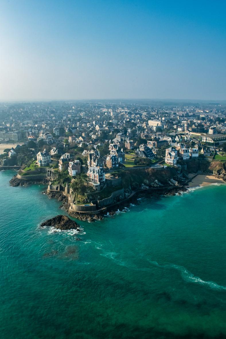Villas historiques sur la falaise de la Pointe de la Malouine à Dinard bordée par une mer emeraude limpide.
