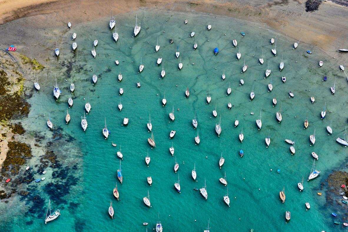 Vue aérienne de voiliers blancs dispersés sur les eaux turquoise translucides du Port du Béchet à Saint-Briac.