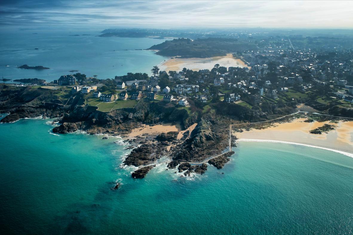Côte rocheuse escarpée et mer turquoise à Saint-Lunaire. Vue aérienne du littoral breton, des plages et des habitations.
