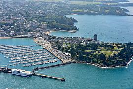 Vue aérienne du port des Bas Sablons à Saint-Malo avec bateaux alignés, la Cité d’Aleth arborée et un ferry blanc à quai.