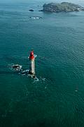 Phare blanc à dôme rouge isolé en pleine mer turquoise. Vue plongeante sur les courants marins près des côtes de Saint-Malo.