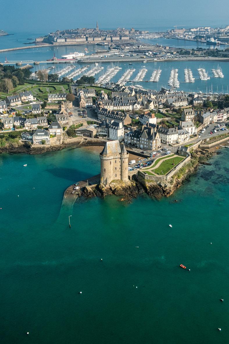Tour Solidor fortifiée au bord d’une mer turquoise, cité d’Aleth et mâts de voiliers du port de Saint-Malo vus du ciel.