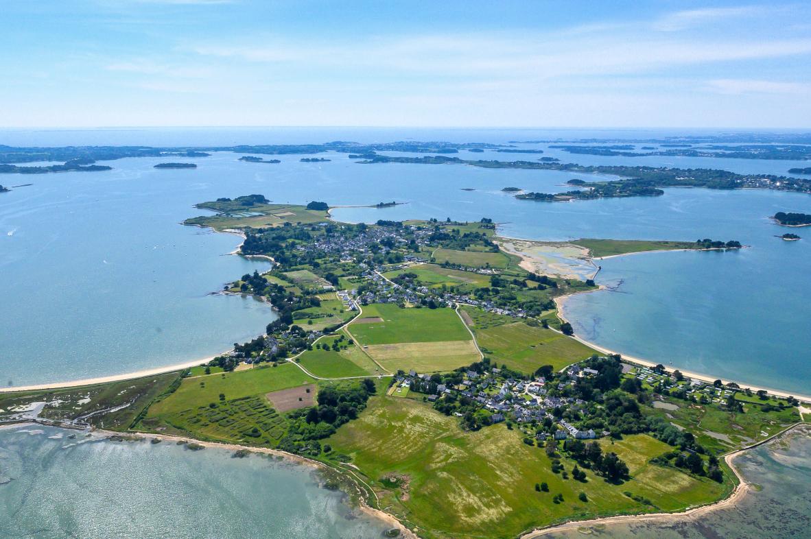 Panorama aérien de l’île d’Arz révélant ses champs verts, son littoral sablonneux et les eaux bleues du Golfe du Morbihan.