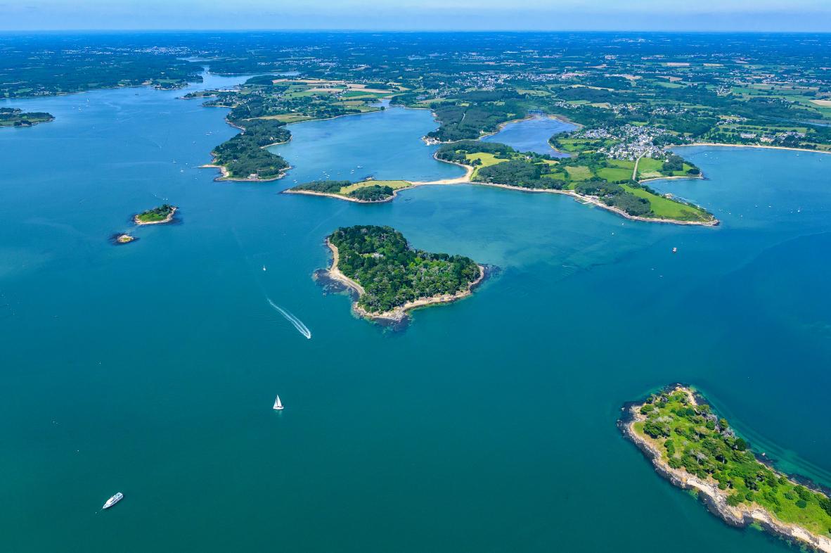 Vue aérienne des îles Er Runio et Sept Îles dans le Golfe du Morbihan avec eaux bleues et végétation verdoyante.
