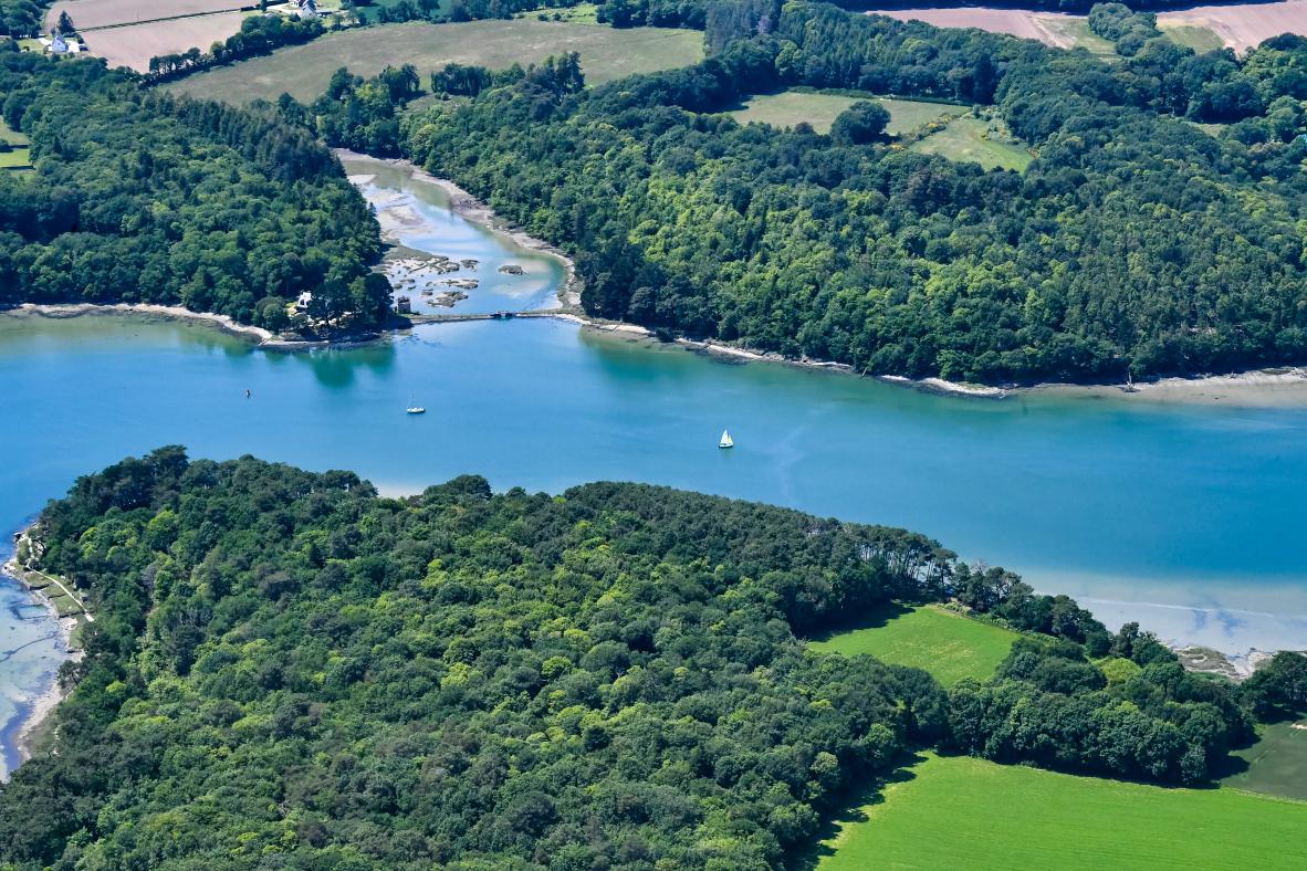 Vue aérienne de la rivière d’Auray entourée de forêts denses et de champs verdoyants à Crac’h dans le Morbihan.
