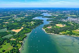 Vue aérienne de la rivière d’Auray et du Bono avec voiliers sur l’eau bleue entourée de forêts verdoyantes en Bretagne.