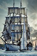 Grand trois-mâts aux voiles blanches déployées naviguant près d’un voilier moderne sur une mer calme en Bretagne.