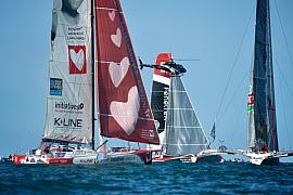 Voiliers de course au large et hélicoptère de suivi sous un ciel bleu lors du départ de la régate au Havre.