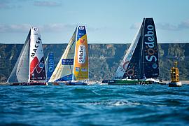 Plusieurs voiliers de course aux voiles colorées Macsf Sodebo St Michel naviguent en mer devant des falaises au Havre