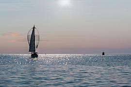 Voilier naviguant avec son spi gonflé sur une mer calme scintillante sous la lumière matinale à Paimpol.