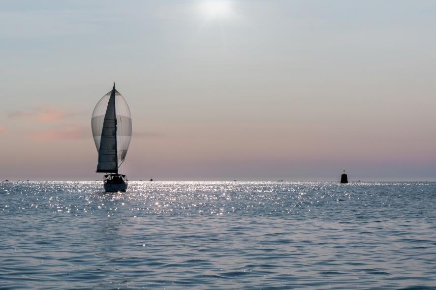 Voilier naviguant avec son spi gonflé sur une mer calme scintillante sous la lumière matinale à Paimpol.