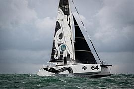 Catamaran GDD blanc et noir sur mer agitée, voiles avec motif poulpe, navigation sportive sous ciel gris.