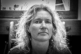 Portrait noir et blanc de Kristen Neuschafer, regard fixe, cheveux bouclés et lumière contrastée.