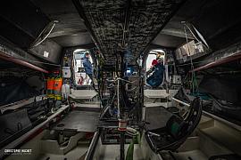 Intérieur technique du voilier IMOCA Lazare avec cockpit en carbone et marins aux écoutilles à Saint-Malo.